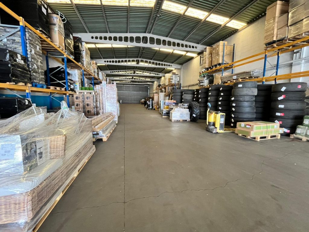 Interior del almacén de Transportes Sixto con mercancías organizadas en estanterías y palés.